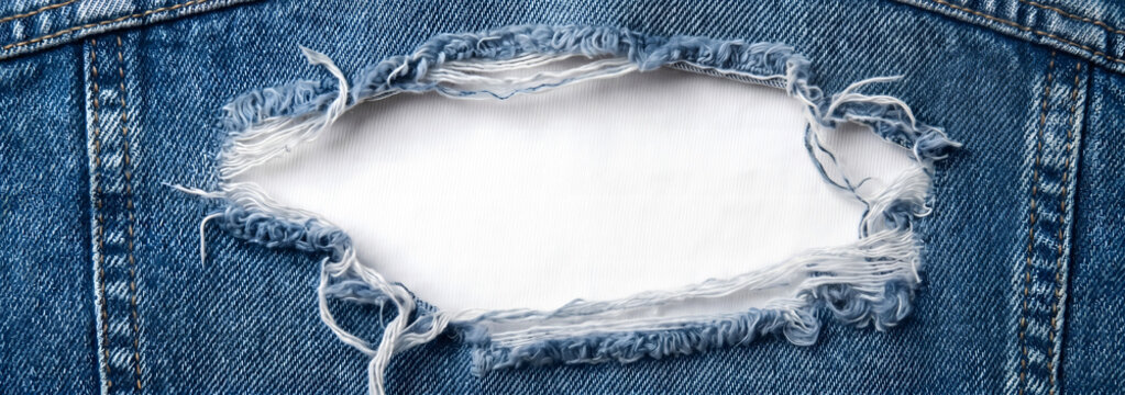 Ripped blue denim jeans texture with white background hole.