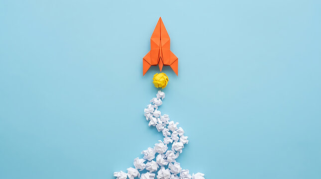 Creative Orange Origami Paper Rocket Launching with Crumpled White Paper Trail on Blue Background