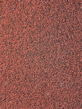 Red rubber running track surface texture background athletics stadium flooring closeup