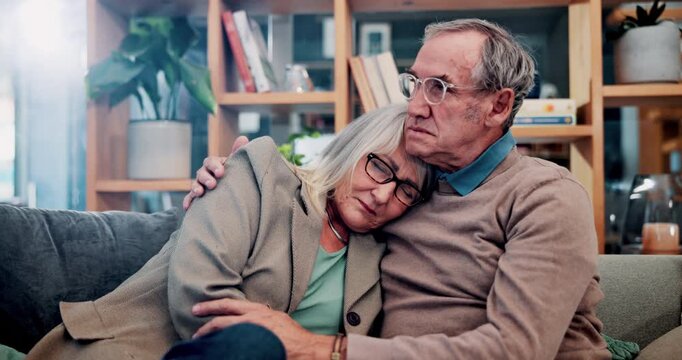 Sad, hug and senior couple on home sofa for support, comfort and empathy for person with depression. Embrace, man and woman in retirement together with love, mental health and sorry for loss in house