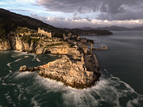 Aerial view of the Church of Saint Peter and Doria Castle on the rocky coastline with rugged cliffs and turquoise sea in Porto Venere, Liguria, Italy.