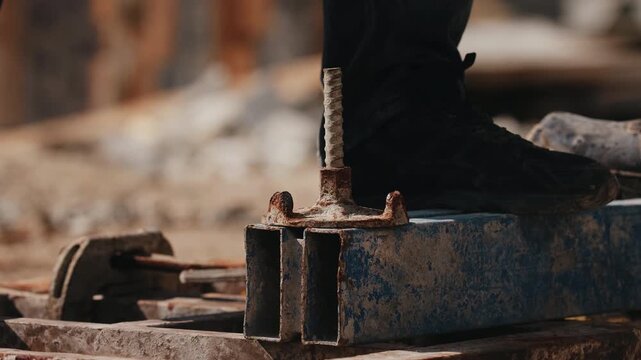 Worker tightening formwork wing nut with hammer during assembly