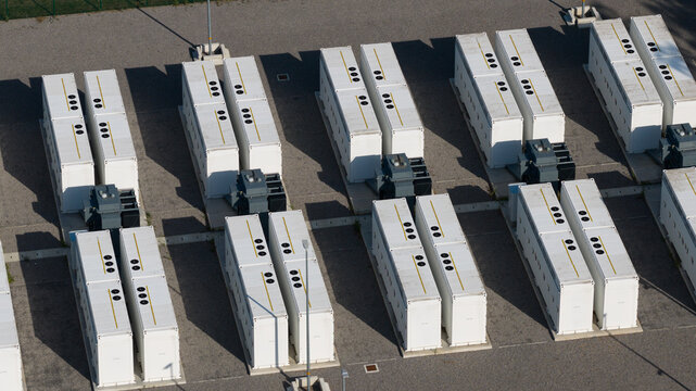 Aerial view of industrial battery energy storage units arranged in rows at a power facility in Le Roeulx, Wallonia, Belgium.