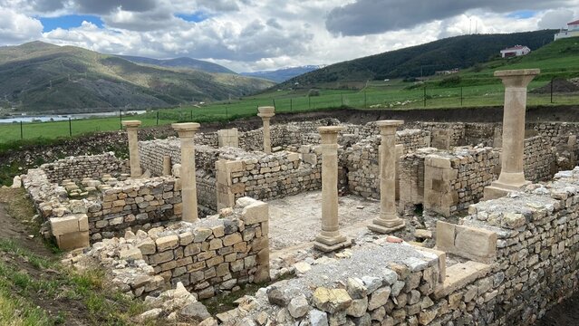 Ancient ruins of Satala Ancient City in Kelkit, G&uuml;m&uuml;şhane, T&uuml;rkiye. Historic Roman archaeological site featuring stone foundations and columns set against a dramatic cloudy sky and lush green landscap