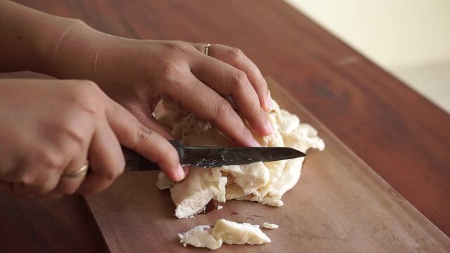 Close up woman hand slicing beef fat (suet) on wooden cutting board for tallow making, traditional food preparation process