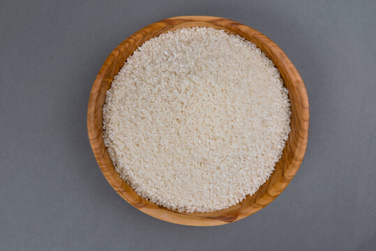 Cuenco de madera lleno de arroz sobre fondo gris