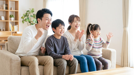 Fototapeta premium リビングのソファで動画や映画を見ておうち時間を楽しむ仲良し家族