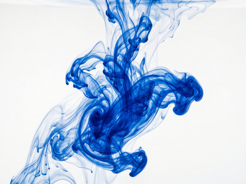 Ink clouds swirl in clear water creating abstract blue patterns against a bright white background.
