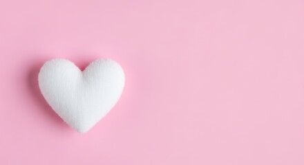 Fototapeta premium A soft white plush heart shape on a solid pastel pink background