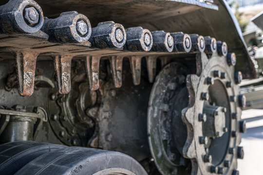 Tracked running gear of self propelled artillery vehicle in close up view, track links, drive sprocket and armored military machinery details from the Soviet era