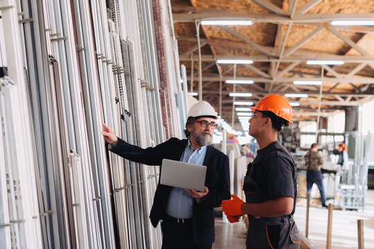 Professionals discussing window profiles in factory showroom