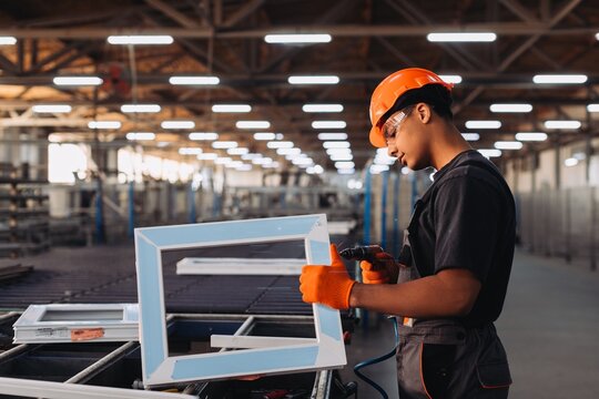 Worker fabricating window frame in factory production