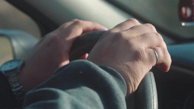 Slow-motion close-up video of a man's hands gripping the steering wheel with intense frustration. Concept of road danger, driving awareness, automotive risks, and road safety.
