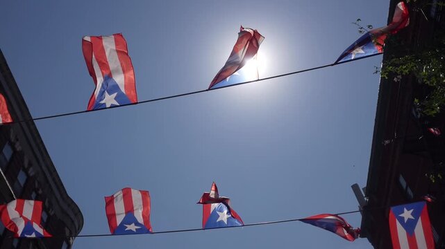 Four Puerto Rican flags waving in the wind against a clear blue sky on a sunny day

