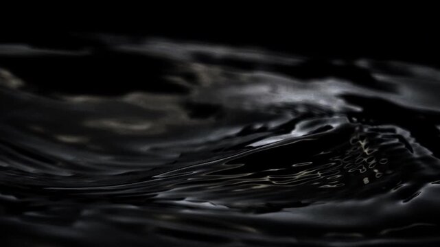 Dark water or black liquid waves moving in slow motion. Abstract moody texture of fluid ripples with soft light reflections on black background, 