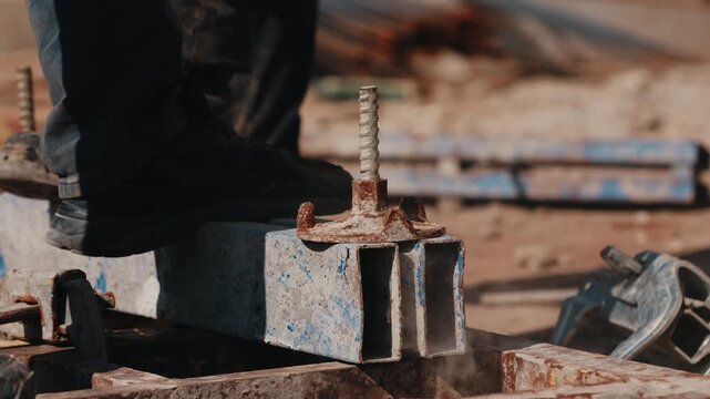 Worker hammering formwork wing nut on tie rod during assembly