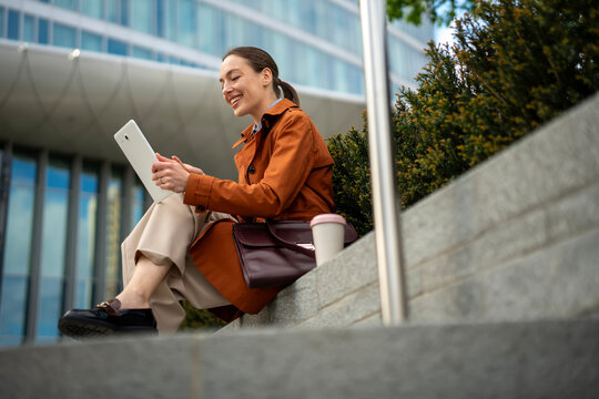 Woman smiling using digital tablet outdoors in city