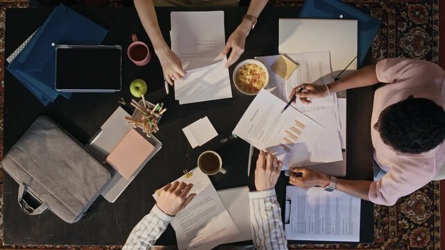 Overhead shot of professionals analyzing charts and documents during collaborative business meeting in modern office