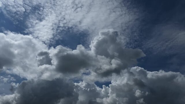 Spectacular time lapse of white and gray cumulus and cirrus clouds drifting through a blue summer sky
