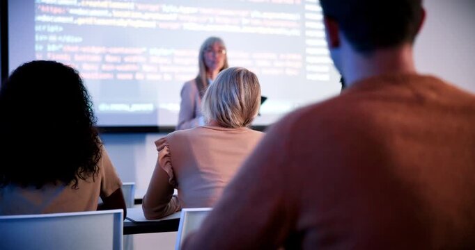 Students, teacher and raised hand in classroom at campus, talk and coding course for education. Person, IT professor and questions with tech, learning and screen for programming in university hall