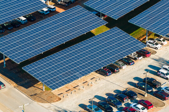 Photovoltaic canopy over parking area producing renewable electricity. Solar panels provide shade for vehicles while generating sustainable energy integrated into city infrastructure.