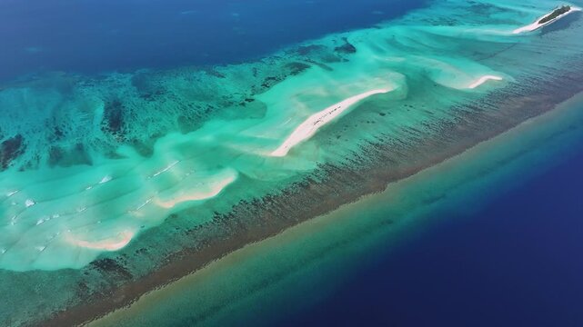 Aerial view of turquoise coral reefs and white sandbars stretching across the crystal clear ocean waters in Fulhadhoo, Baa Atoll, Maldives.