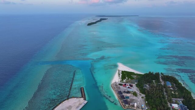 Aerial view of the tropical island of Fulhadhoo with white sand beaches, lush vegetation, and vibrant turquoise lagoons and coral reefs in Fulhadhoo, Baa Atoll, Maldives.
