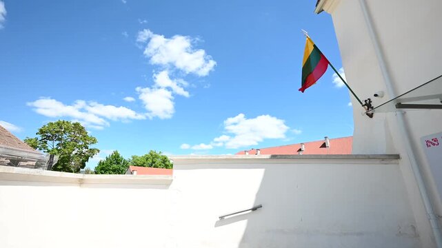 The vibrant Lithuanian flag proudly flutters against a bright blue sky filled with white clouds, showcasing national pride and a beautiful day in the historic city of Vilnius, Lithuania