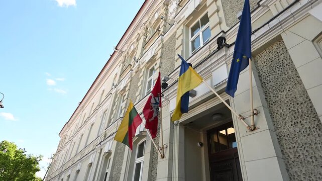 Lithuanian, Ukrainian, and European Union flags flying proudly on a sunny day from a historic building in Vilnius, Lithuania, symbolizing international unity and support.