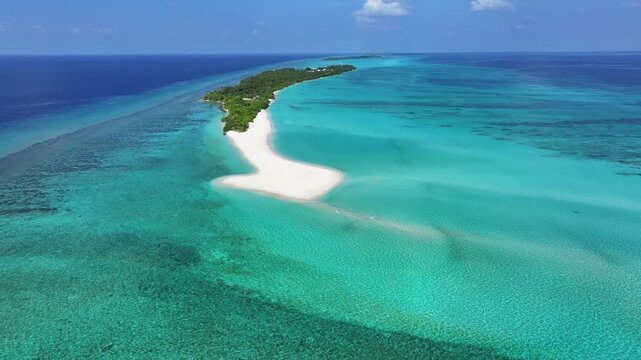 Aerial view of the long white sand beach and lush tropical vegetation of Fulhadhoo island surrounded by turquoise coral reefs in Fulhadhoo, Baa Atoll, Maldives.
