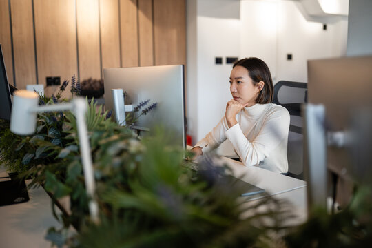 Asian woman working focused at computer in office