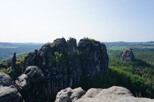 Panorama view of the mountains and valley landscape of the landmark Schrammsteine mountain range from its peak on a sunny summer day