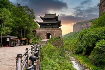 Obraz premium Ancient Jianmen Guanlou gate tower surrounded by steep mountain cliffs in Jianmen Pass, Sichuan, China