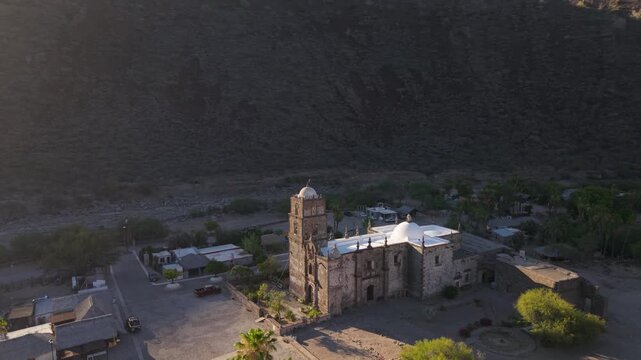 Explore sunrise aerial views of San Javier Mission in Baja California Sur, Mexico, alongside lush palm trees near Loreto