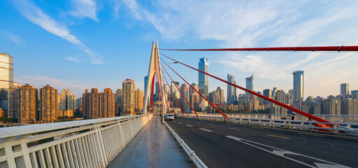 Fototapeta premium Pedestrian walkway on Qiansimen Bridge leading to the white pylon and Jiefangbei skyscrapers skyline in Chongqing, China