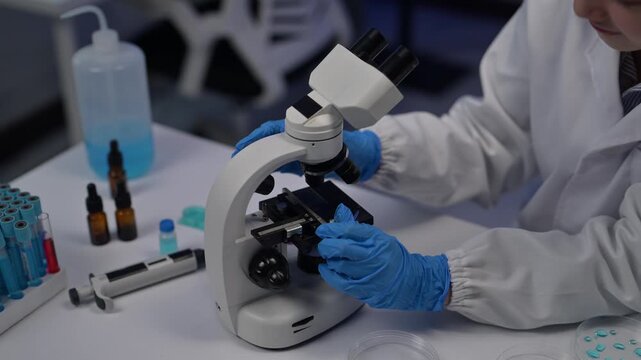 Scientist adjusting microscope slide in laboratory