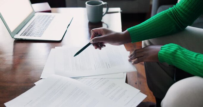 Focused African American Woman Reviewing Documents with Laptop and Pen on a Coffee Table