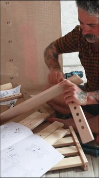 Tattooed man assembling flat pack furniture