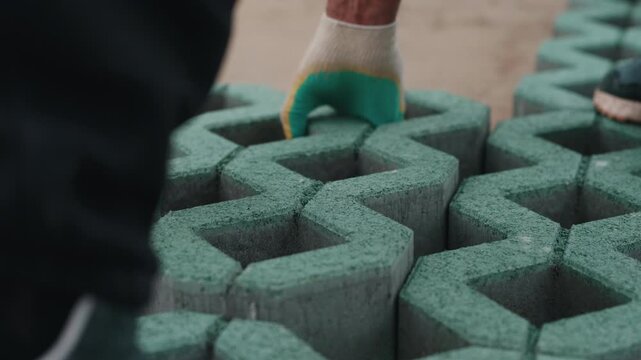 Worker fitting interlocking grass grid blocks during paving installation