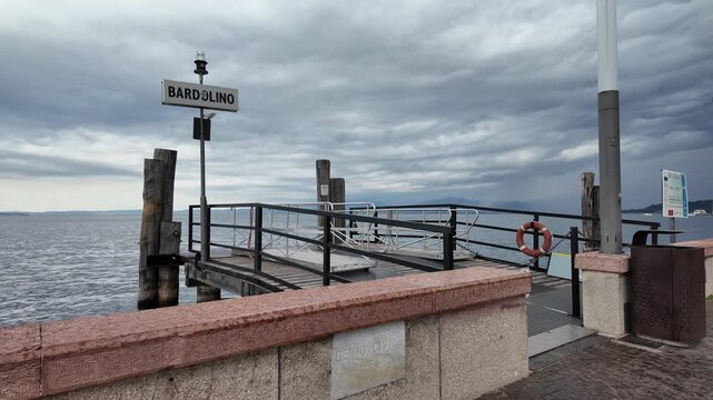 Bardolino, Italy - May 14, 2026 - Bardolino ferry terminal on a cloudy day with calm water