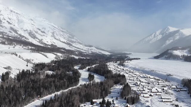 Epic aerial over snow village river valley and mountains in Xinjiang