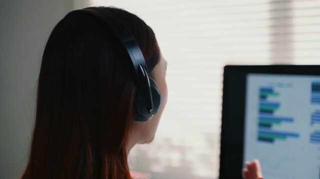 Customer service representative wearing a headset talking to a client. Female agent consulting a customer online while looking at a screen