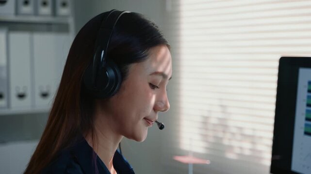 Young Asian woman working in a call center, providing customer service and technical support. A helpful consultant talking to a client