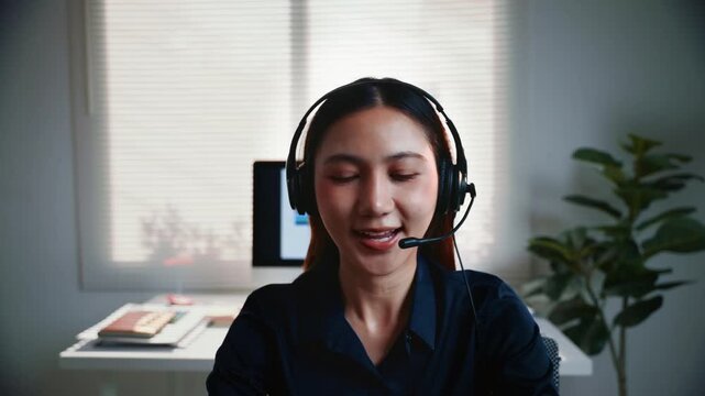 Professional asian woman operator working in a call center, wearing a headset and talking with a customer, providing technical support