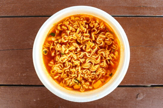 Hot spicy instant cup noodles with chopsticks in a disposable bowl and steaming red broth ready to eat, showcasing popular Korean convenience food and quick meal culture.