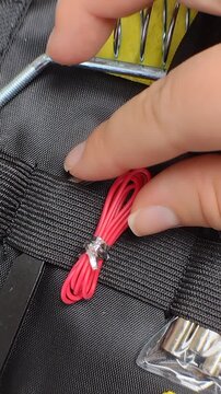 Fingers taking a red wire heat shrink tubing or wire wrap out of a black tool organizer case. Close-up shot, steady camera. Electronics repair, soldering equipment concept video.