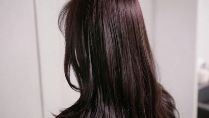 Naklejka premium Close-up of a woman's long, dark brown hair, showcasing its healthy shine and texture, ideal for beauty, haircare, and lifestyle concepts.