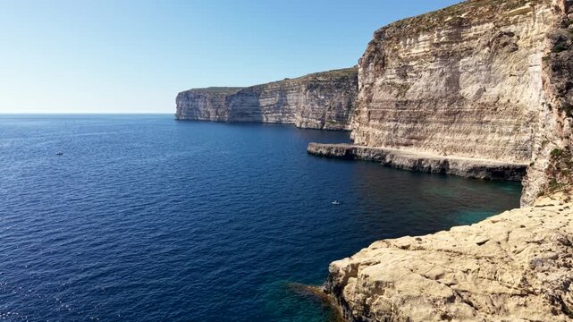 Aerial view of the rugged Xlendi cliffs and deep blue Mediterranean sea along the rocky coastline in Munxar, Gozo Region, Malta.