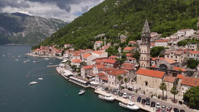 Perast Montenegro 4K Aerial Video, Landscape Drone Pull Back and Elevation Ascent revealing St Nicholas Church Bell Tower, Waterfront Docks, and Mountain Fjord Backdrop