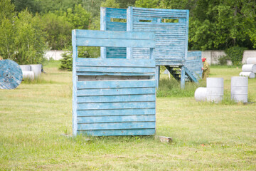 Paintball field with barrels, old tires and blue painted wooden crates for paintball game in summer day © Таня Микитюк